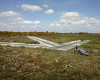 The arrow is on the ridge overlooking the target, close to a bend on the cycle route.
It points directly at the target and would have been illuminated for night bombing.
There is a double row of concrete pads behind it which I suspect supported a building containing the generator.
